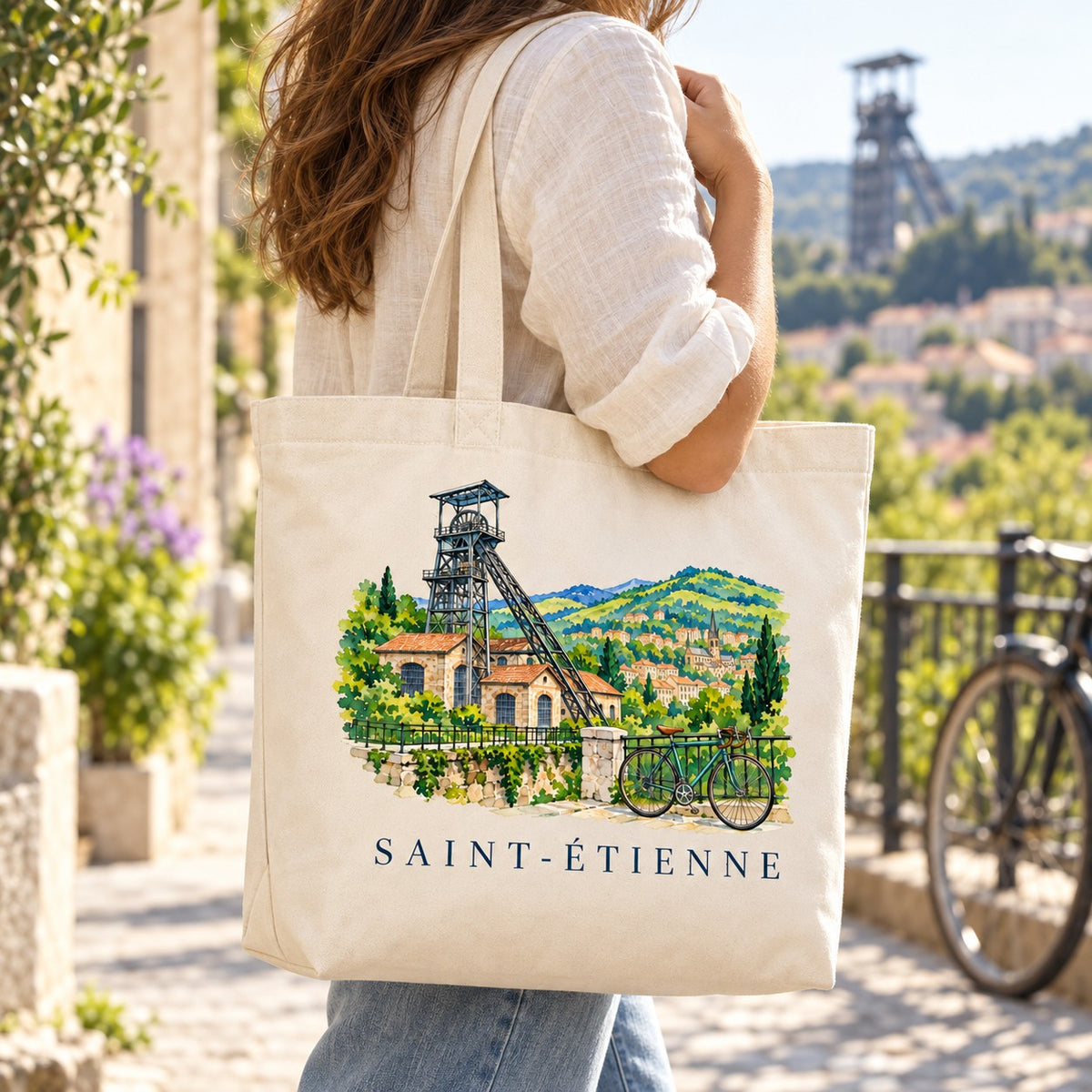 Tote bag Saint-Étienne Premium porté à l'épaule sur un belvédère, chevalement en arrière-plan