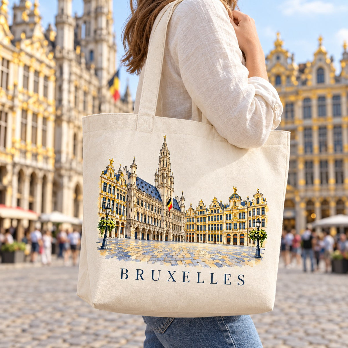 Tote bag Bruxelles Premium porté à l'épaule sur la Grand-Place, maisons des corporations en arrière-plan