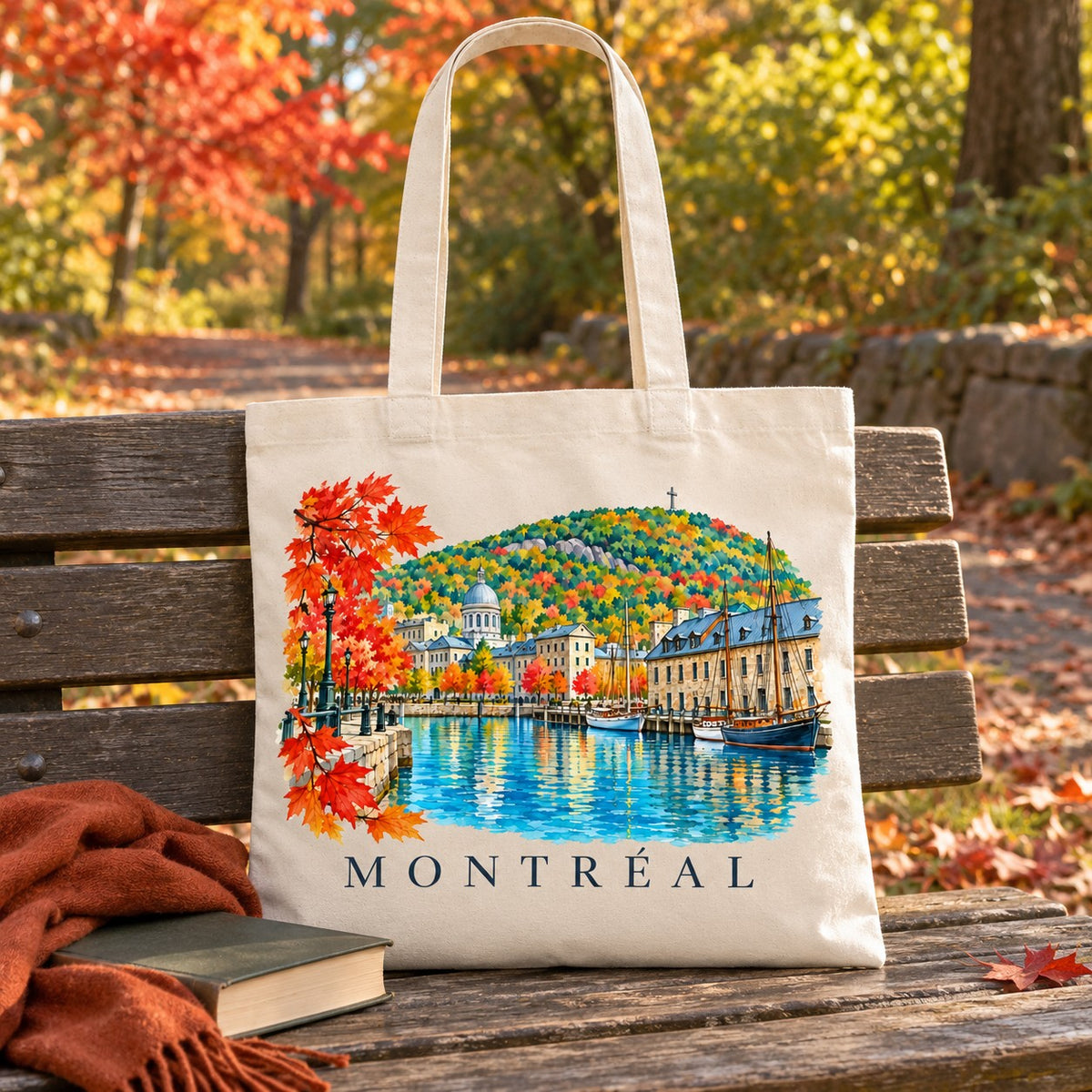 Tote bag Montréal Essentiel posé sur un banc sous les érables rouges, avec un livre et un plaid