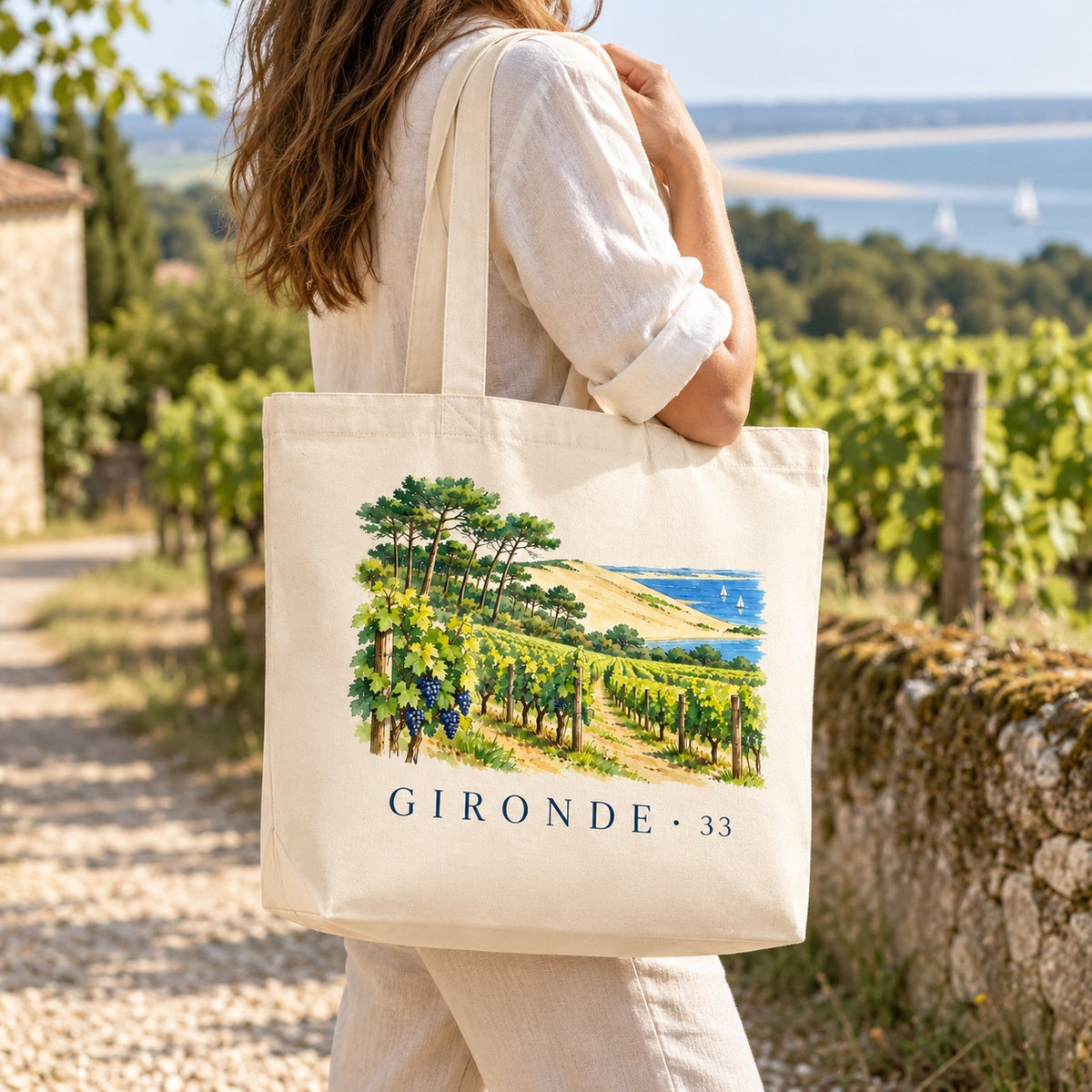 Tote bag Gironde (33) Premium porté à l'épaule sur un chemin entre les vignes, bassin en arrière-plan