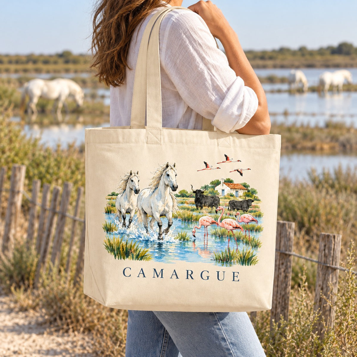Tote bag Camargue Premium porté à l'épaule au bord des étangs, chevaux blancs en arrière-plan
