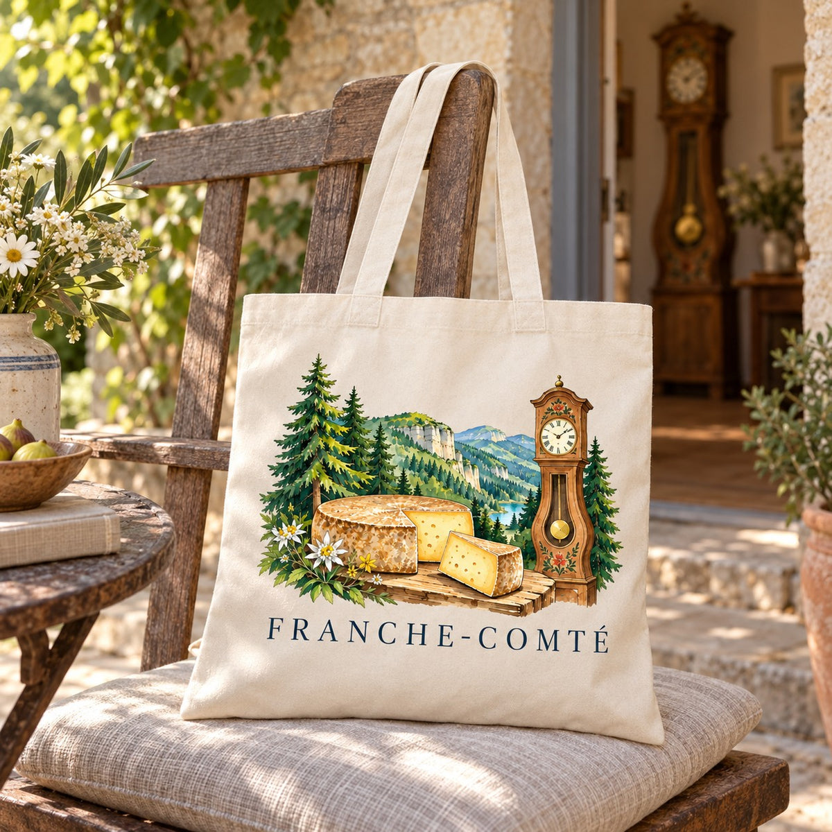 Tote bag Franche-Comté Essentiel suspendu à une chaise de bois garnie d'un coussin, à côté d'une horloge comtoise