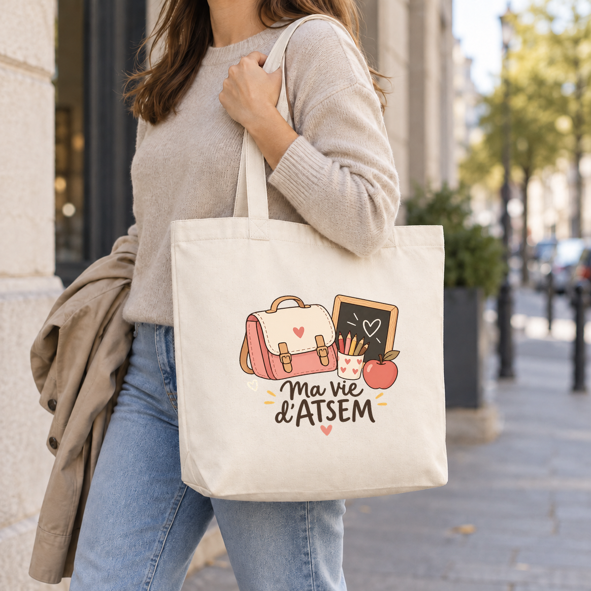 Tote bag ATSEM « Ma vie d'ATSEM » Premium porté à l'épaule dans la rue, en arrivant à l'école — visuel centré selon le gabarit validé