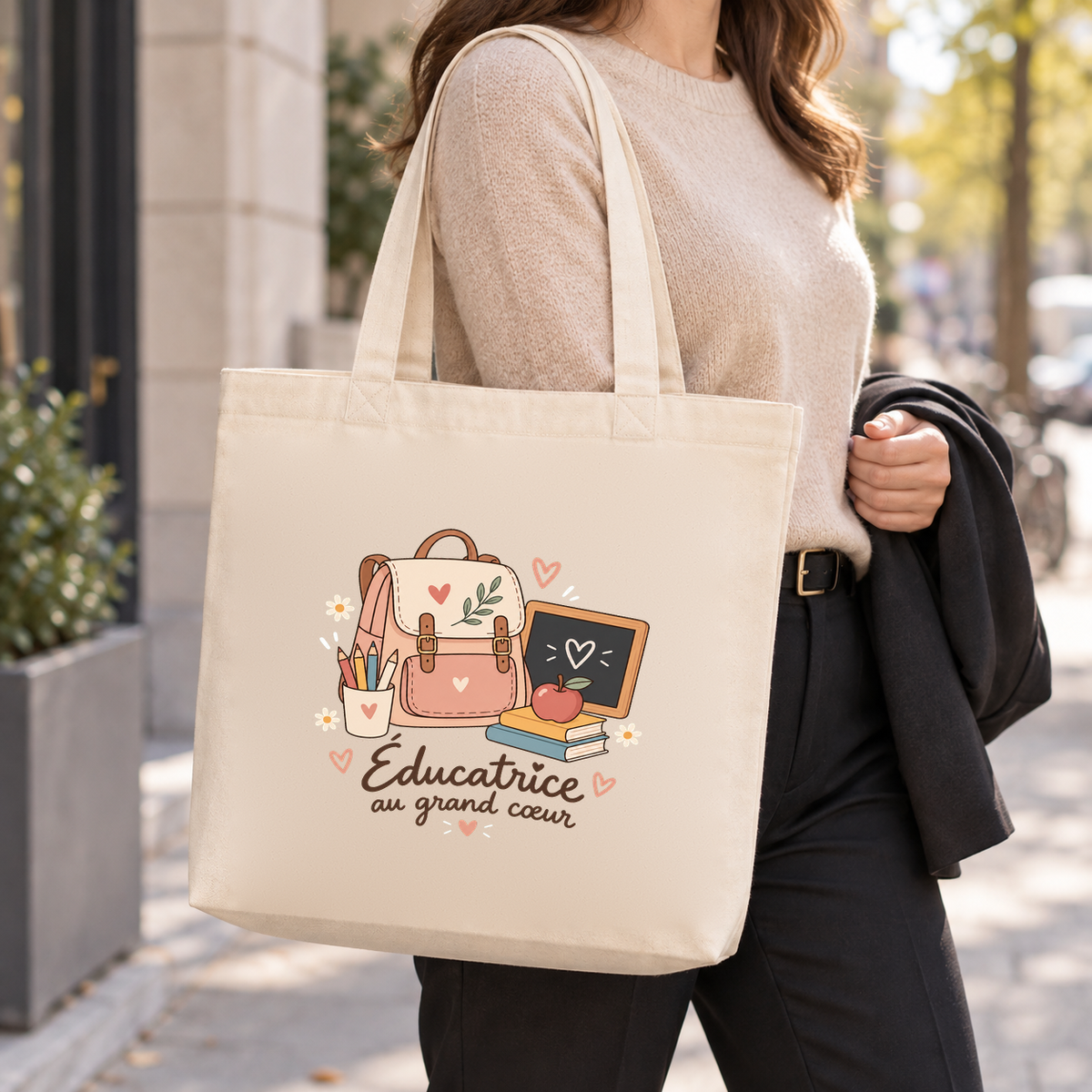 Tote bag éducatrice spécialisée « Éducatrice au grand cœur » Premium porté à l'épaule dans la rue, une veste sur le bras