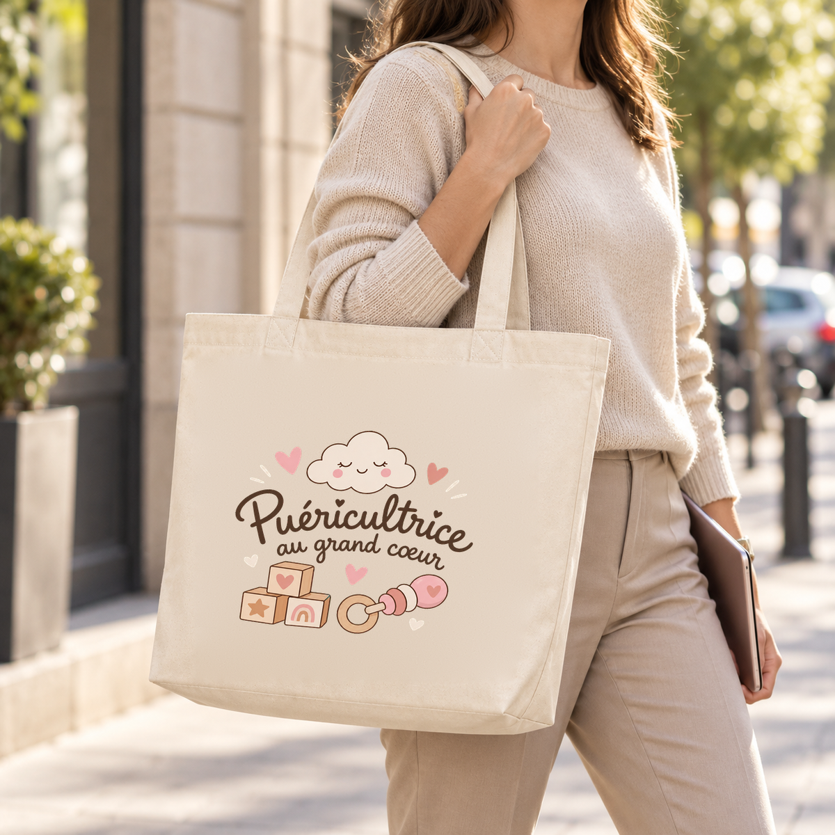 Tote bag puéricultrice « Puéricultrice au grand cœur » Premium porté à l'épaule dans la rue, un dossier à la main