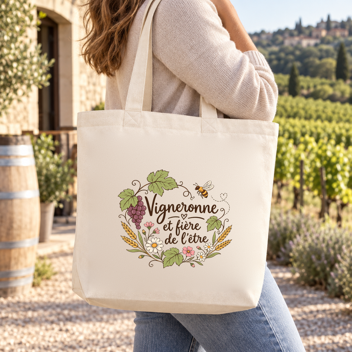 Tote bag vigneronne « Vigneronne et fière de l'être » Premium porté à l'épaule devant les vignes, près d'un tonneau