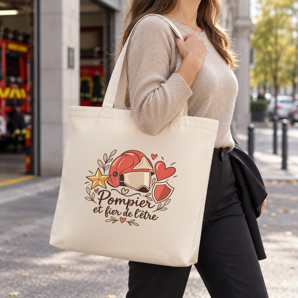 Tote bag pompier « Pompier et fier de l'être » Premium porté à l'épaule dans la rue, devant une caserne