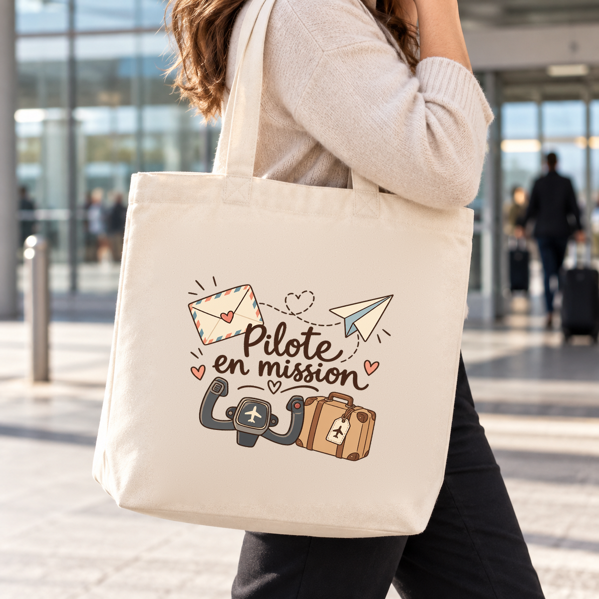Tote bag pilote « Pilote en mission » Premium porté à l'épaule dans un hall d'aéroport