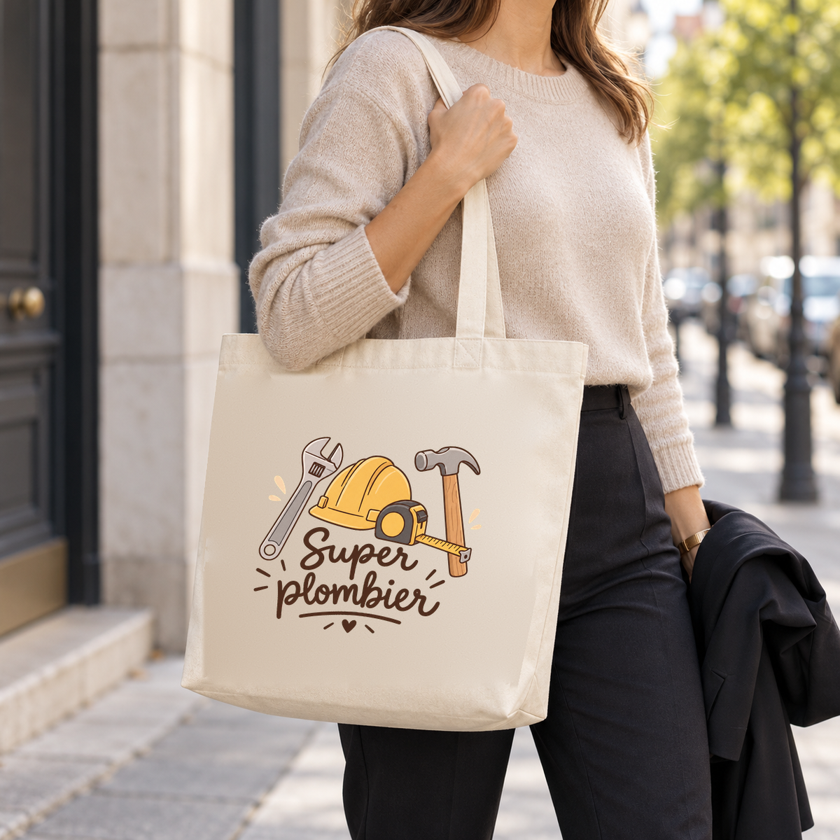 Tote bag plombier « Super plombier » Premium porté à l'épaule dans la rue, une veste sur le bras