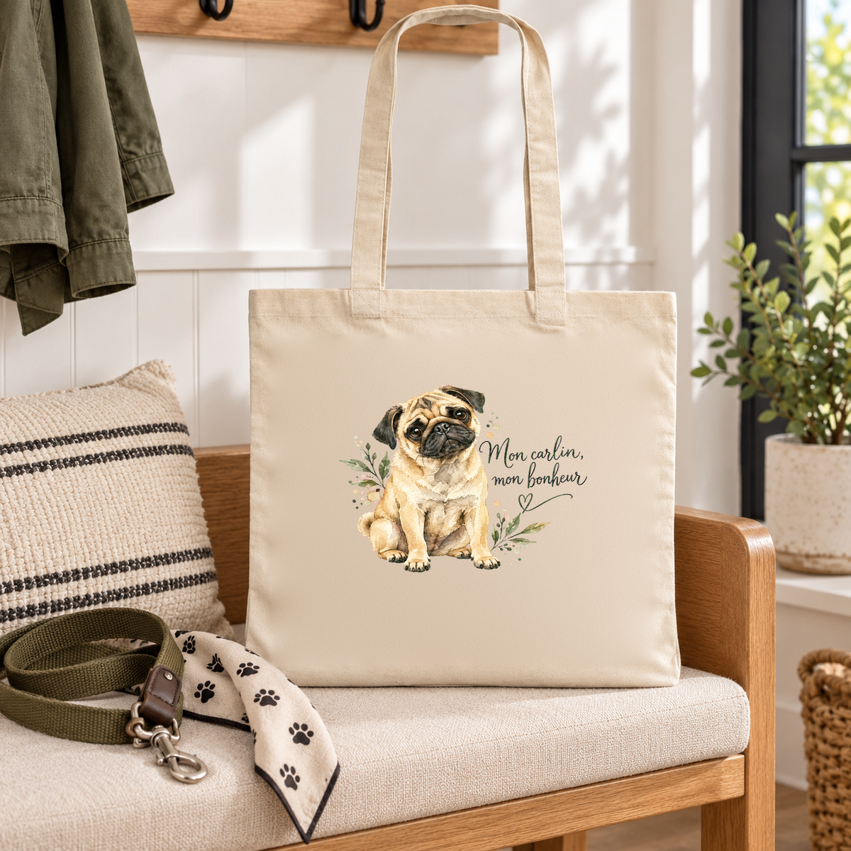 Tote bag carlin « Mon carlin, mon bonheur » Essentiel posé sur une banquette d'entrée, à côté d'une laisse et d'un bandana