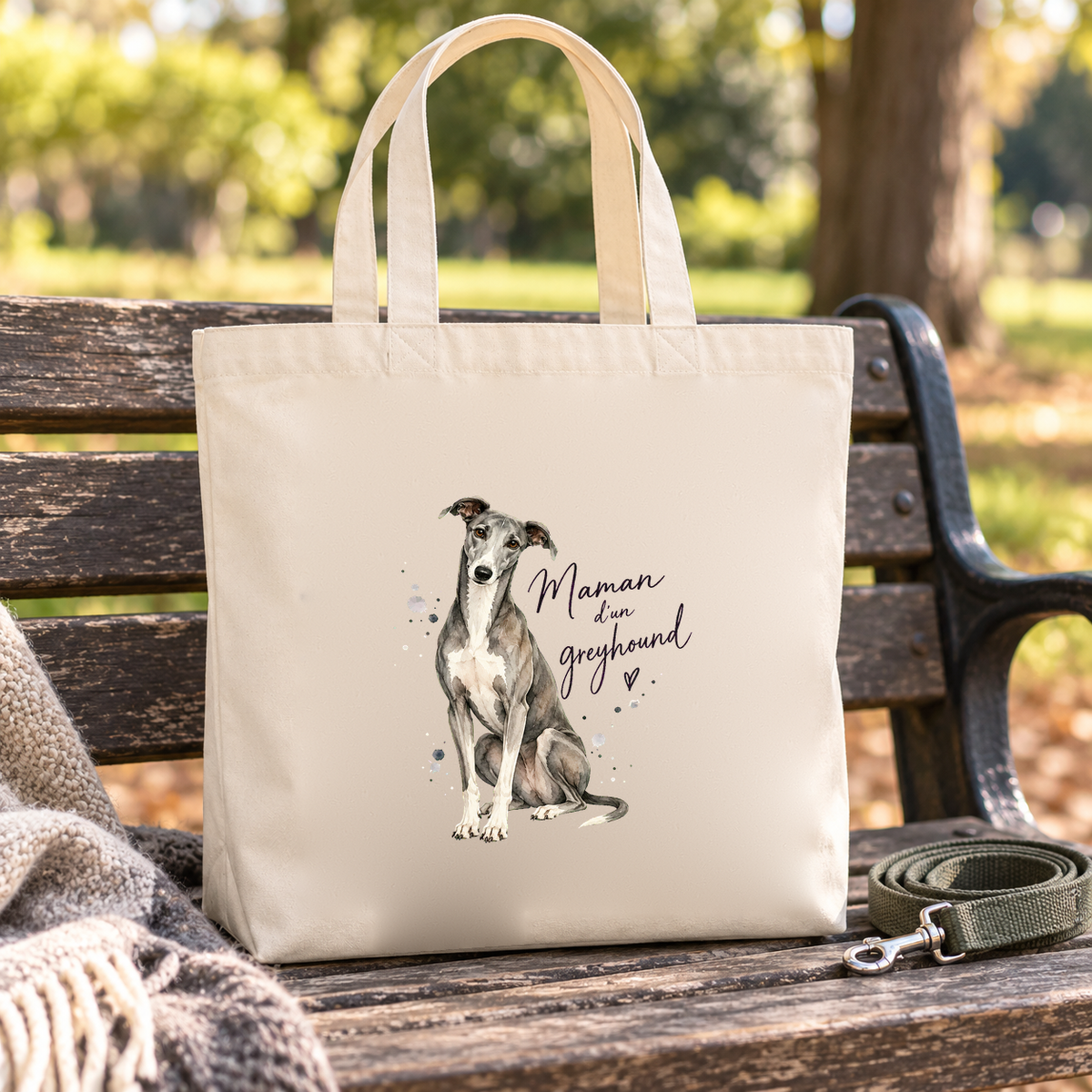 Tote bag greyhound « Maman d'un greyhound » Premium posé sur un banc de parc, à côté d'une laisse
