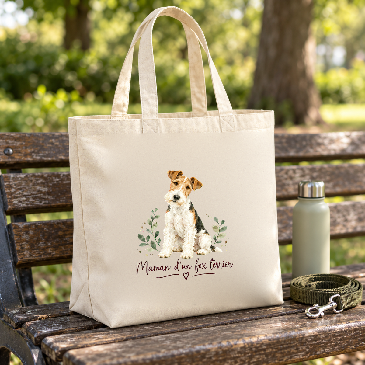 Tote bag fox terrier « Maman d'un fox terrier » Premium posé sur un banc de parc, à côté d'une gourde et d'une laisse