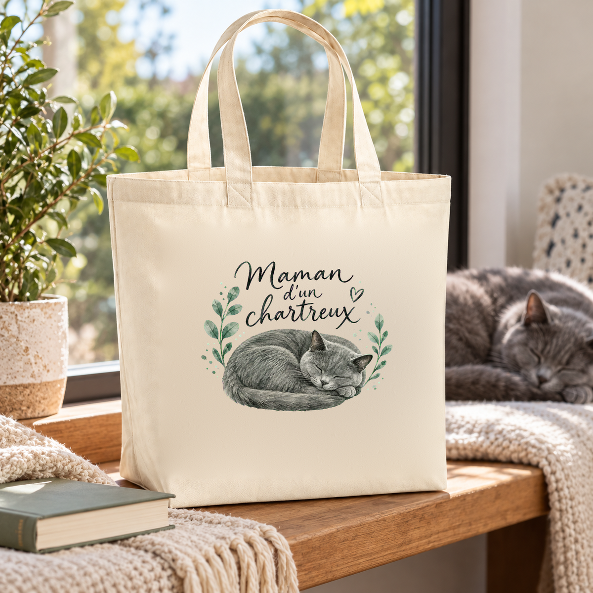 Tote bag chartreux « Maman d'un chartreux » Premium posé sur une banquette près de la fenêtre, à côté d'un chartreux