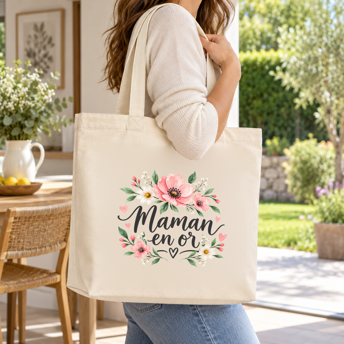Tote bag maman « Maman en or » Premium porté à l'épaule sur une terrasse fleurie, lors d'une promenade au jardin