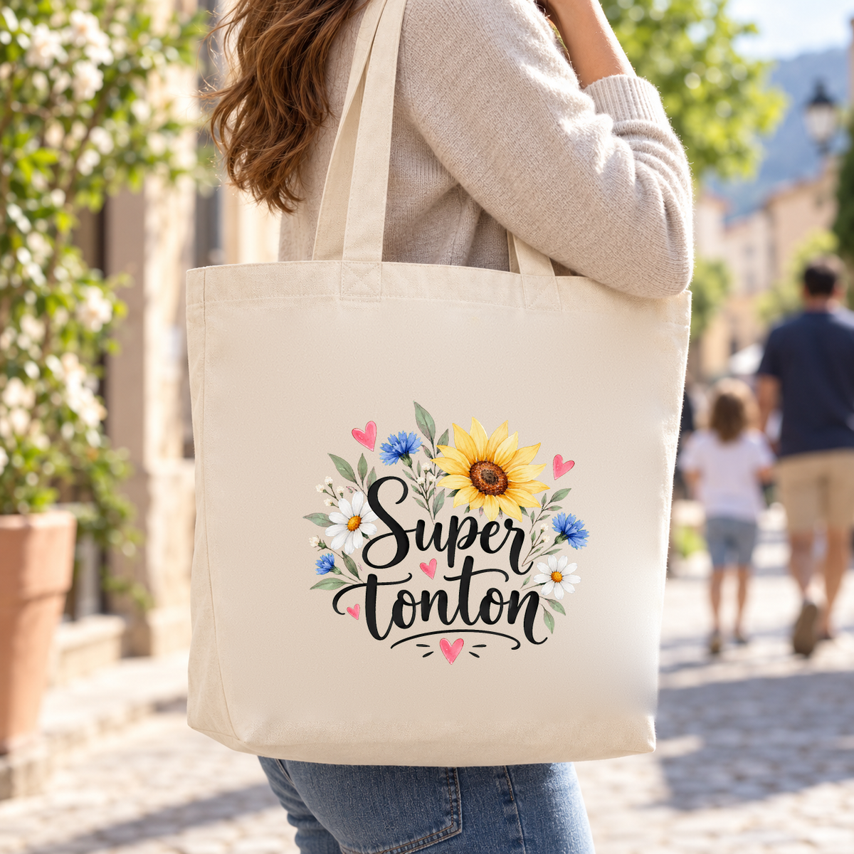 Tote bag tonton « Super tonton » Premium porté à l'épaule dans une rue ensoleillée, lors d'une promenade en famille