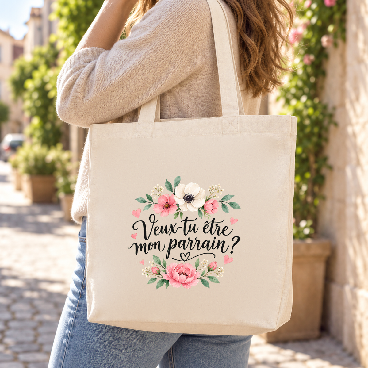 Tote bag parrain « Veux-tu être mon parrain ? » Premium porté à l'épaule dans une ruelle fleurie