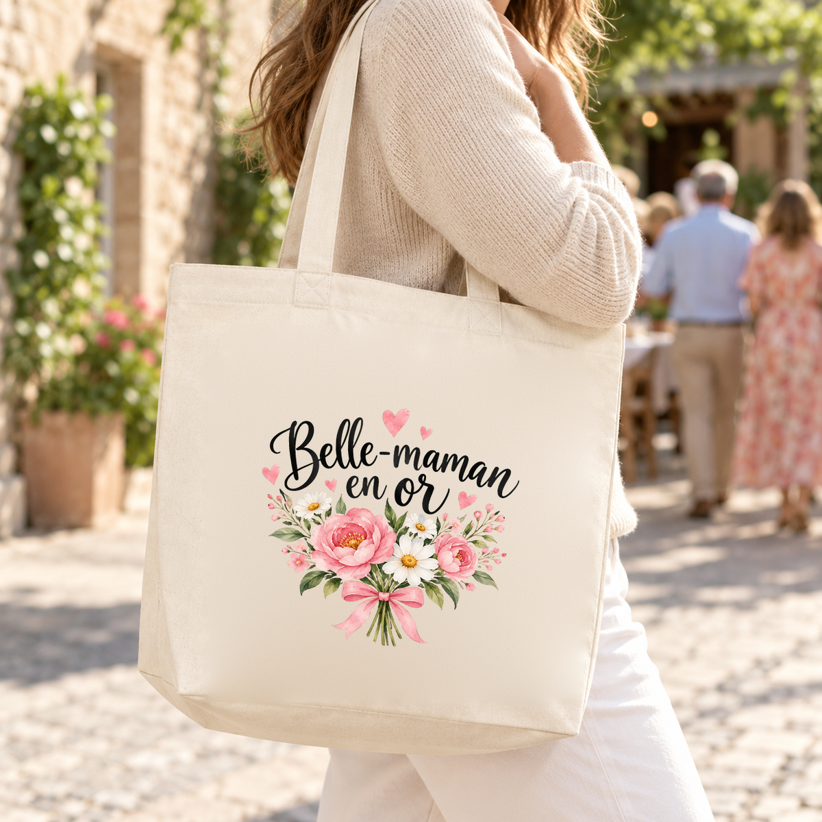Tote bag belle-maman « Belle-maman en or » Premium porté à l'épaule dans une rue ensoleillée, en route pour un repas de famille