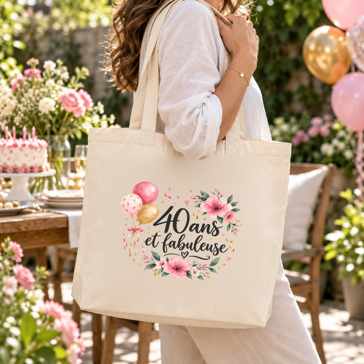 Tote bag anniversaire « 40 ans et fabuleuse » Premium porté à l'épaule lors d'une fête d'anniversaire dans un jardin, entre ballons et fleurs