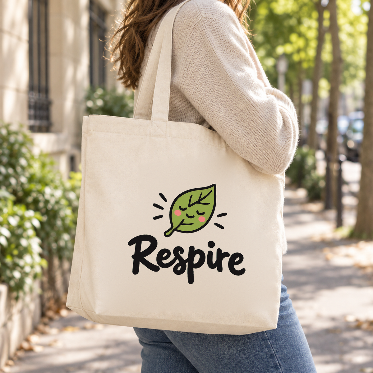 Tote bag « Respire » Premium porté à l'épaule dans une rue calme bordée d'arbres