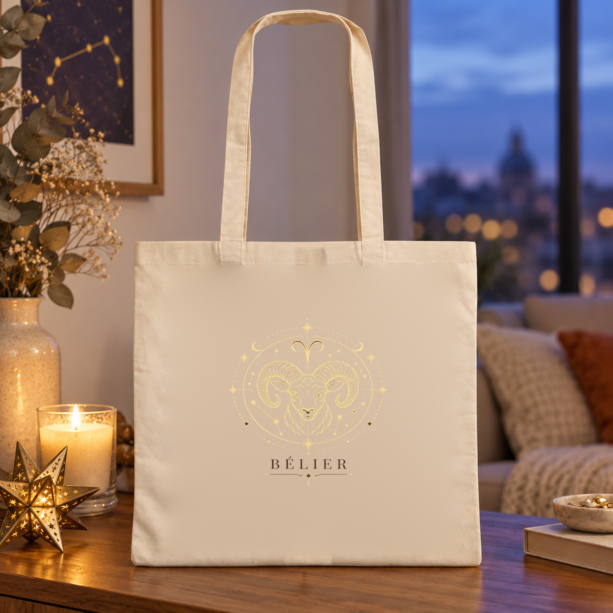 Tote bag signe astrologique « BÉLIER » Essentiel posé sur une table près d'une fenêtre, à côté de bougies, à la tombée de la nuit