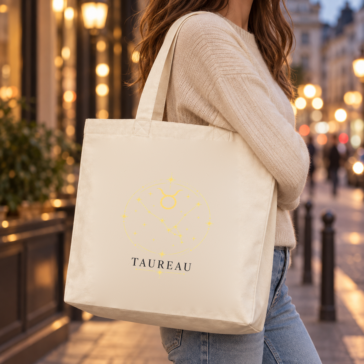 Tote bag signe astrologique « TAUREAU » Premium porté à l'épaule sur un quai de ville au crépuscule