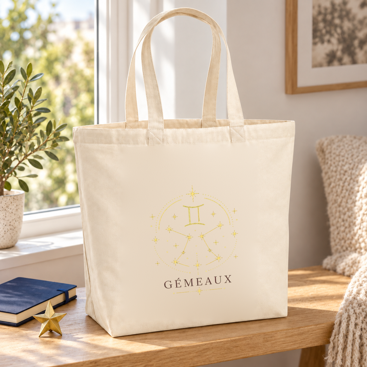 Tote bag signe astrologique « GÉMEAUX » Premium posé sur une table près d'une fenêtre, à côté d'un carnet et d'une petite étoile dorée
