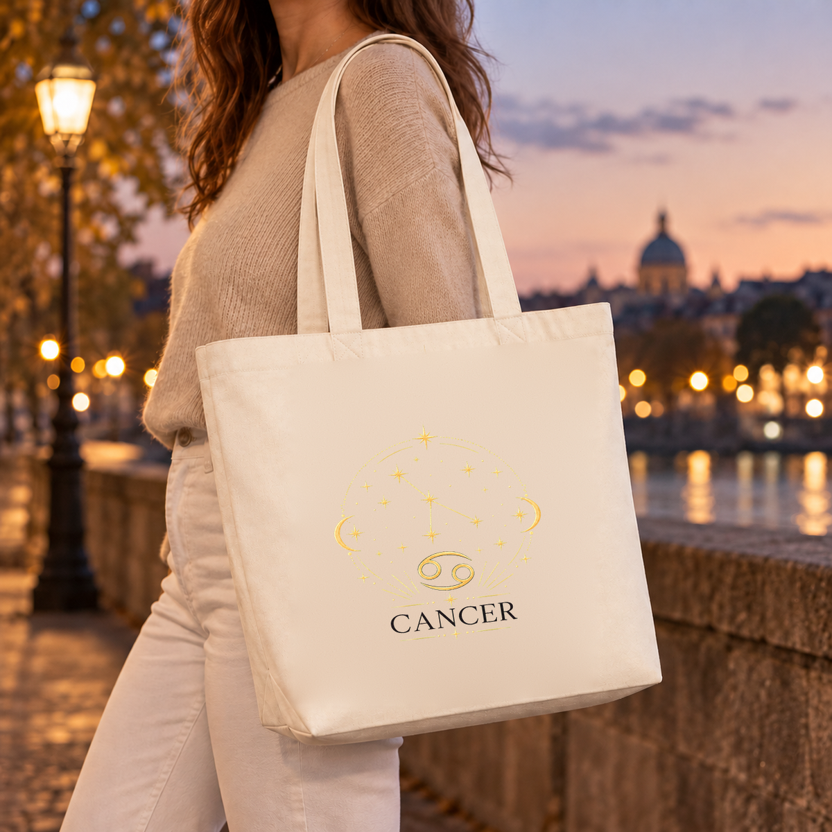 Tote bag signe astrologique « CANCER » Premium porté à l'épaule sur un quai au coucher du soleil