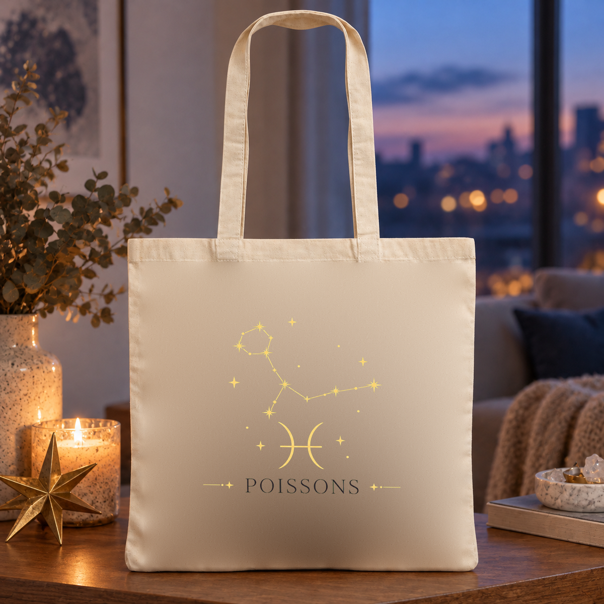 Tote bag signe astrologique « POISSONS » Essentiel posé sur une table près d'une fenêtre, à côté de bougies et d'une étoile dorée, à la tombée de la nuit