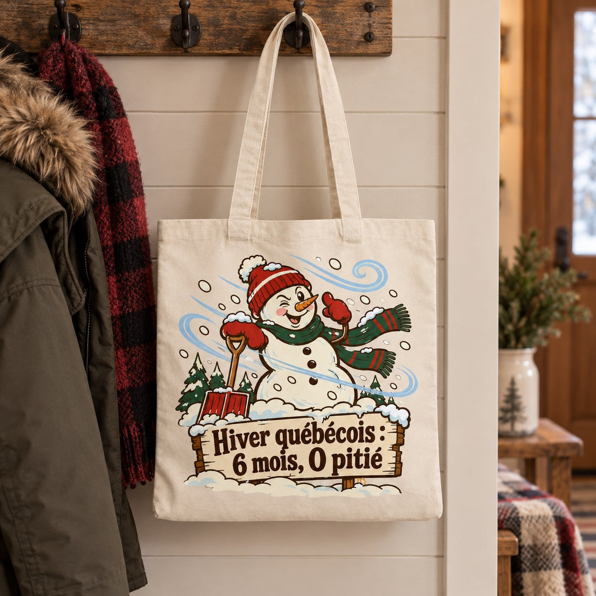 Tote bag « Hiver québécois : 6 mois, 0 pitié » Essentiel suspendu à une patère dans une entrée