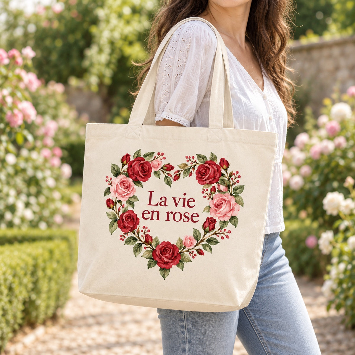 Tote bag « La vie en rose » Premium porté à l'épaule dans un jardin fleuri