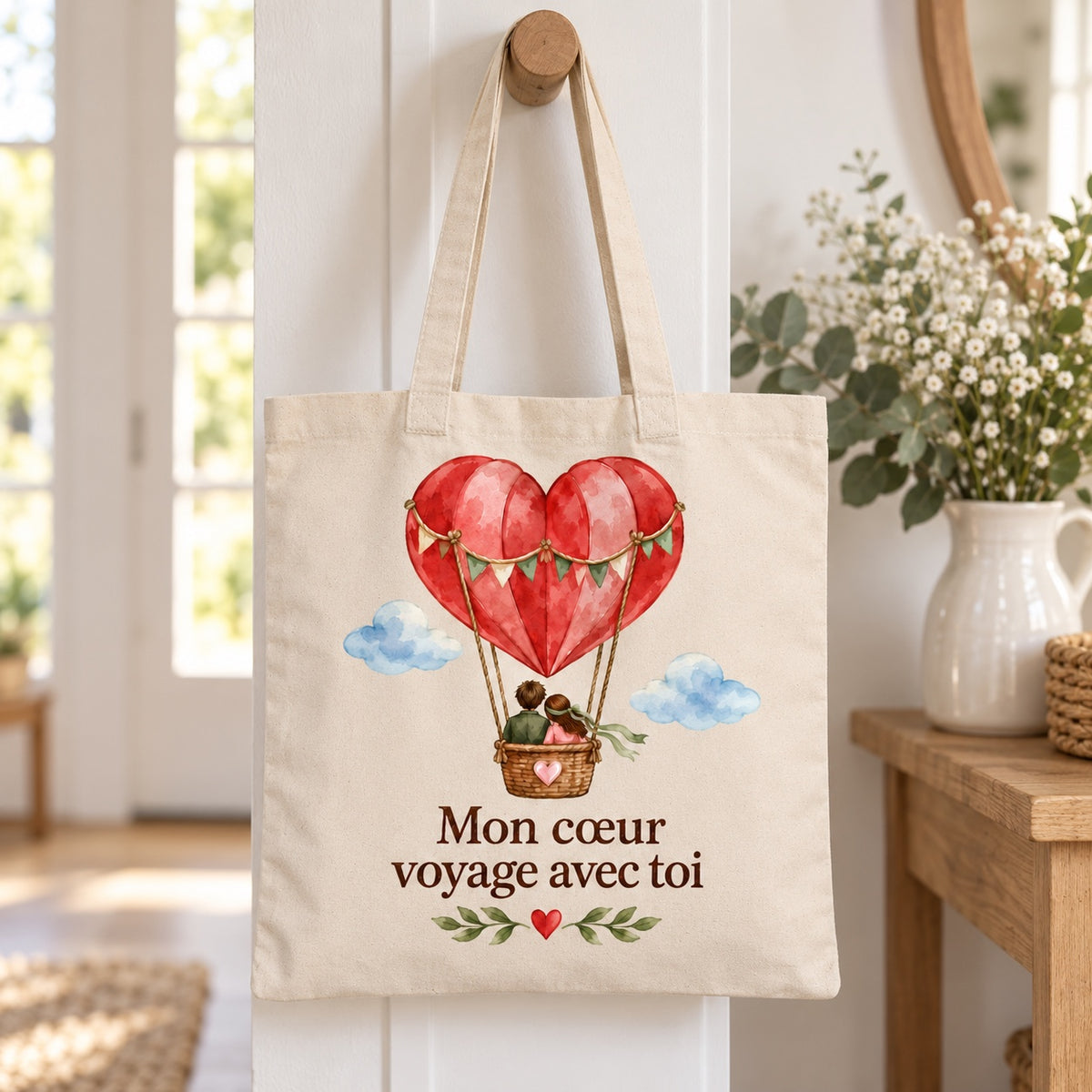 Tote bag « Mon cœur voyage avec toi » Essentiel suspendu à une patère dans une entrée lumineuse