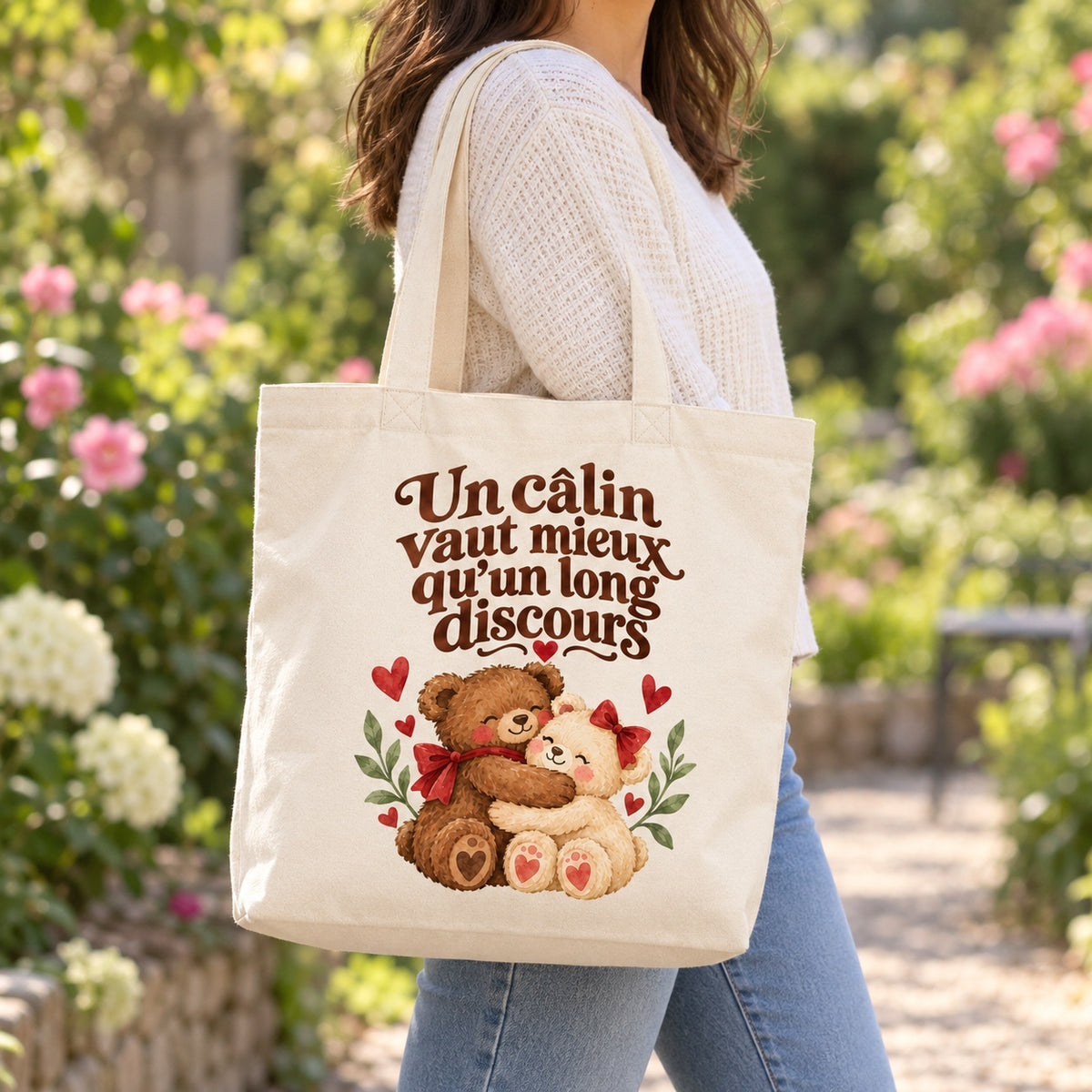 Tote bag « Un câlin vaut mieux qu’un long discours » Premium porté à l'épaule dans un jardin fleuri