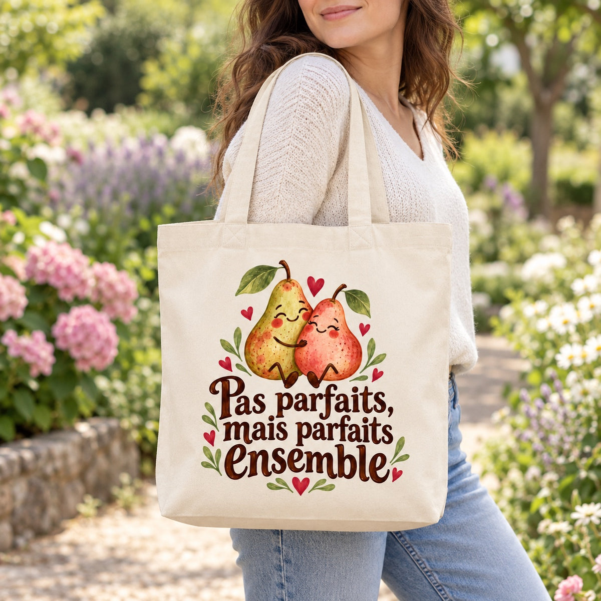Tote bag « Pas parfaits, mais parfaits ensemble » Premium porté à l'épaule dans un jardin fleuri