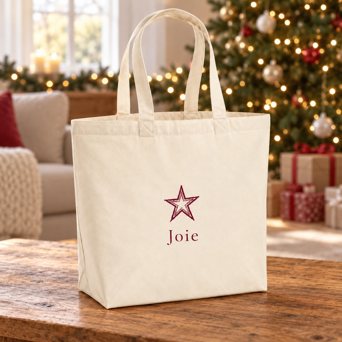 Tote bag de Noël « Joie » Premium posé sur une table de salon devant le sapin
