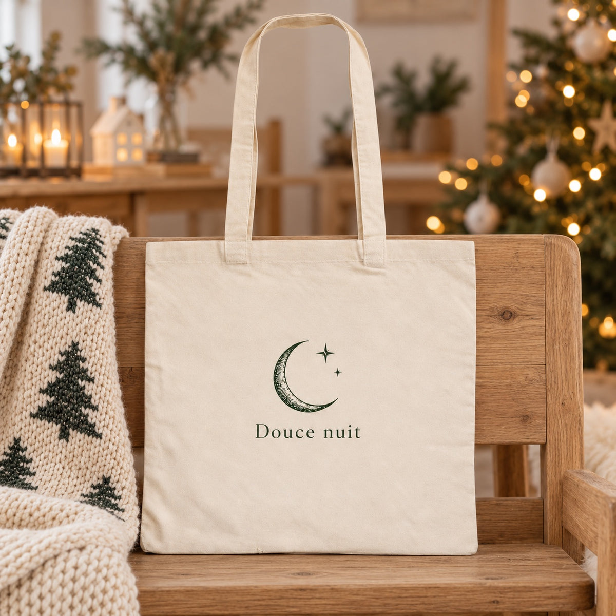 Tote bag de Noël « Douce nuit » Essentiel appuyé contre un banc près d'un plaid de Noël