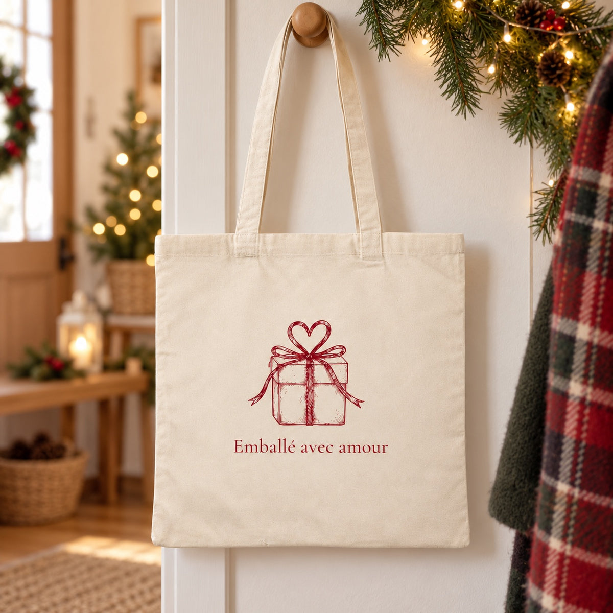 Tote bag de Noël « Emballé avec amour » Essentiel suspendu à une patère dans une entrée décorée pour Noël