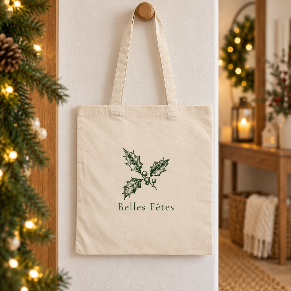 Tote bag de Noël « Belles Fêtes » Essentiel suspendu à une patère dans une entrée décorée pour Noël
