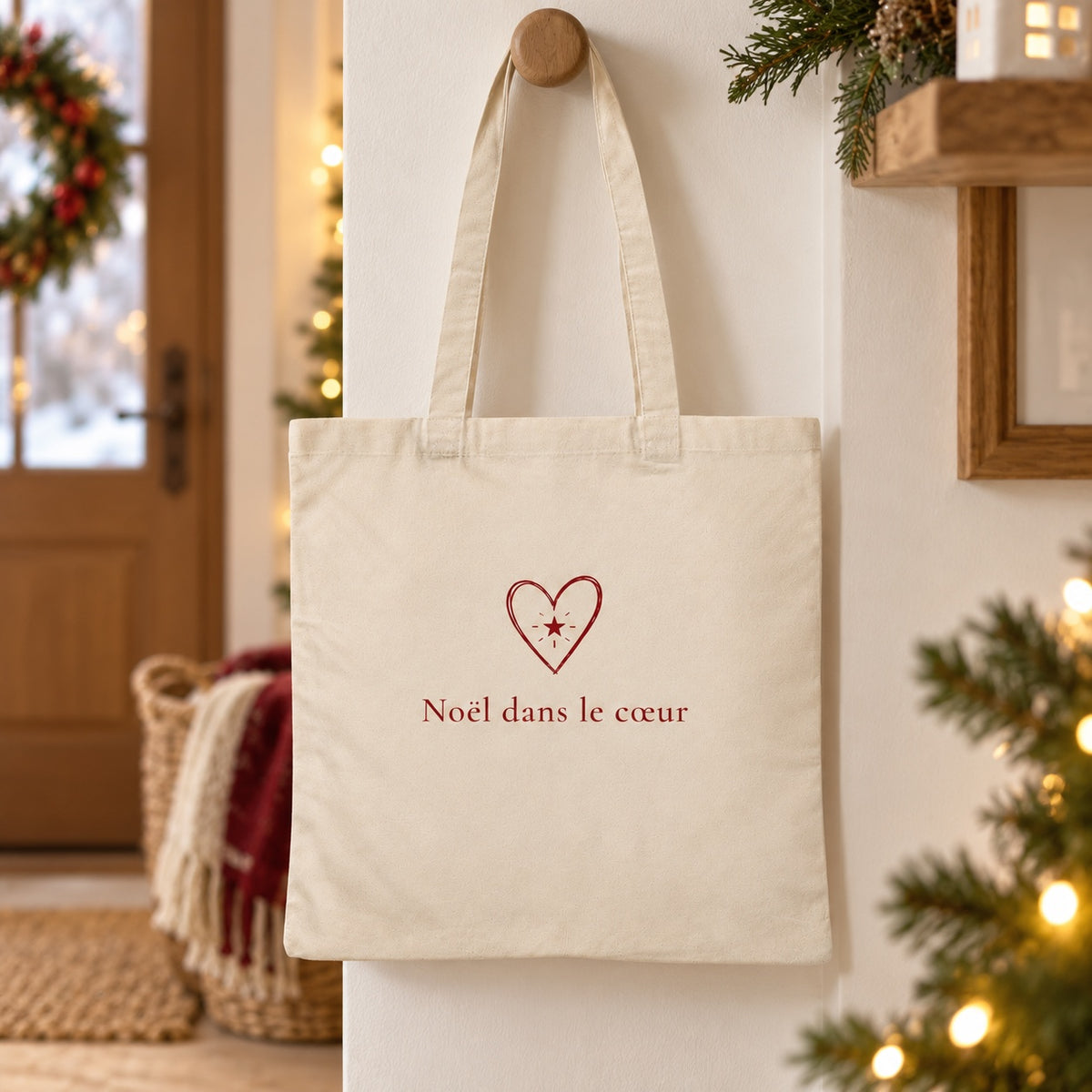 Tote bag de Noël « Noël dans le cœur » Essentiel suspendu à une patère dans une entrée décorée pour Noël