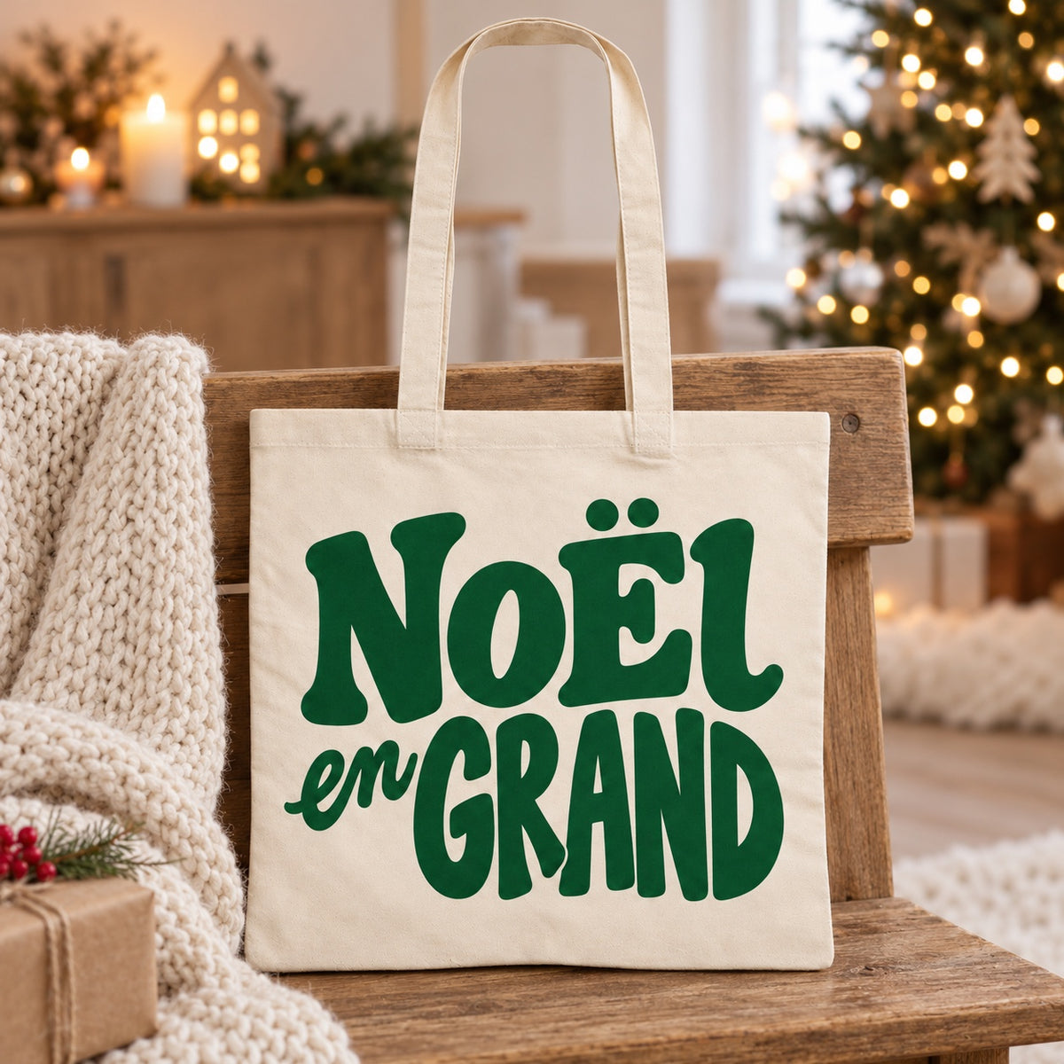 Tote bag de Noël « Noël en grand » Essentiel appuyé contre un banc près d'un plaid de Noël