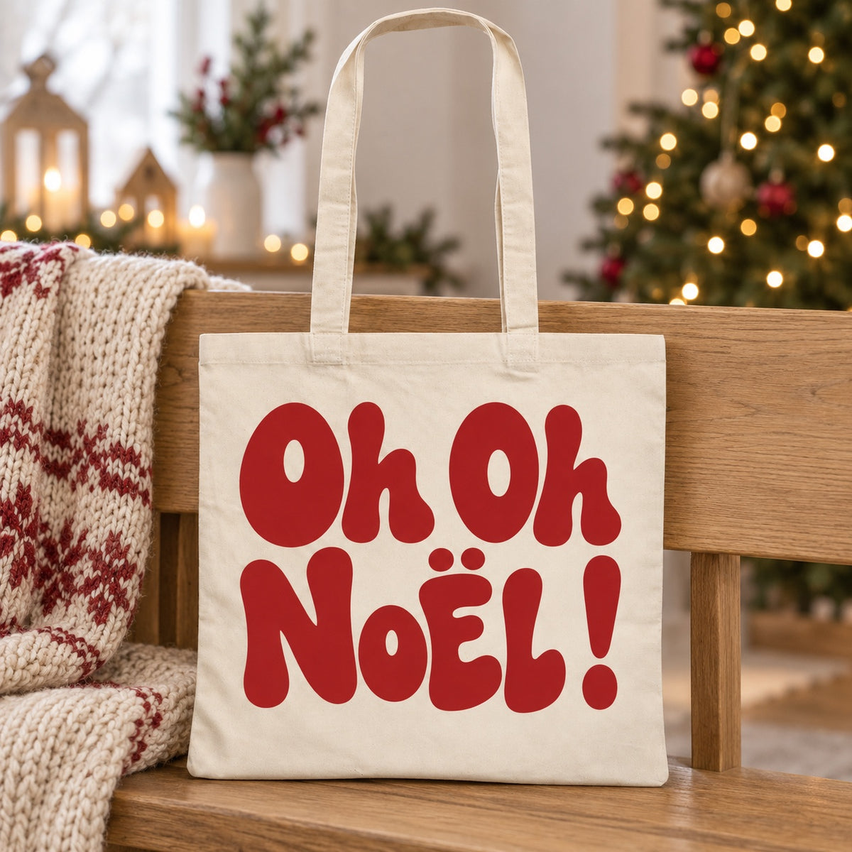 Tote bag de Noël « Oh oh Noël ! » Essentiel appuyé contre un banc près d'un plaid de Noël