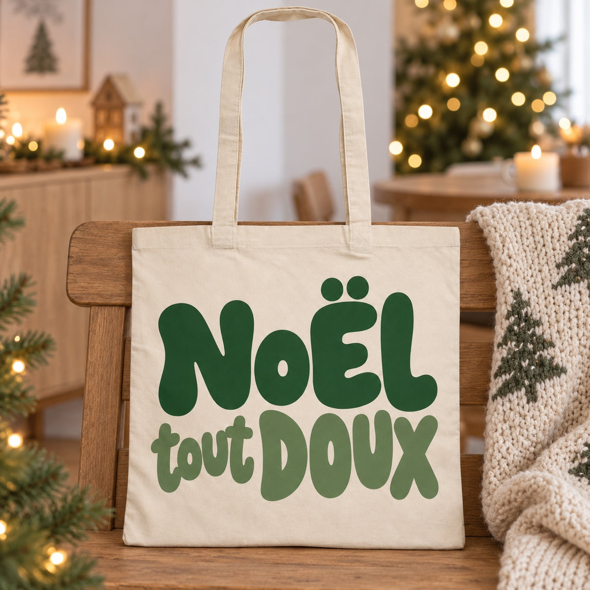 Tote bag de Noël « Noël tout doux » Essentiel appuyé contre un banc près d'un plaid de Noël
