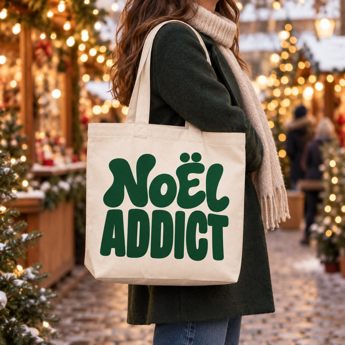 Tote bag de Noël « Noël addict » Premium porté à l'épaule dans un marché de Noël