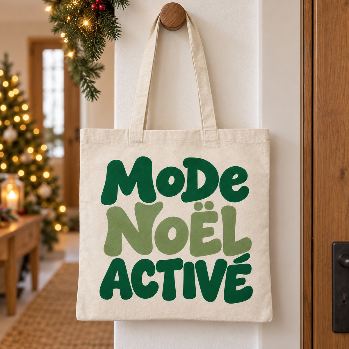Tote bag de Noël « Mode Noël activé » Essentiel suspendu à une patère dans une entrée décorée pour Noël