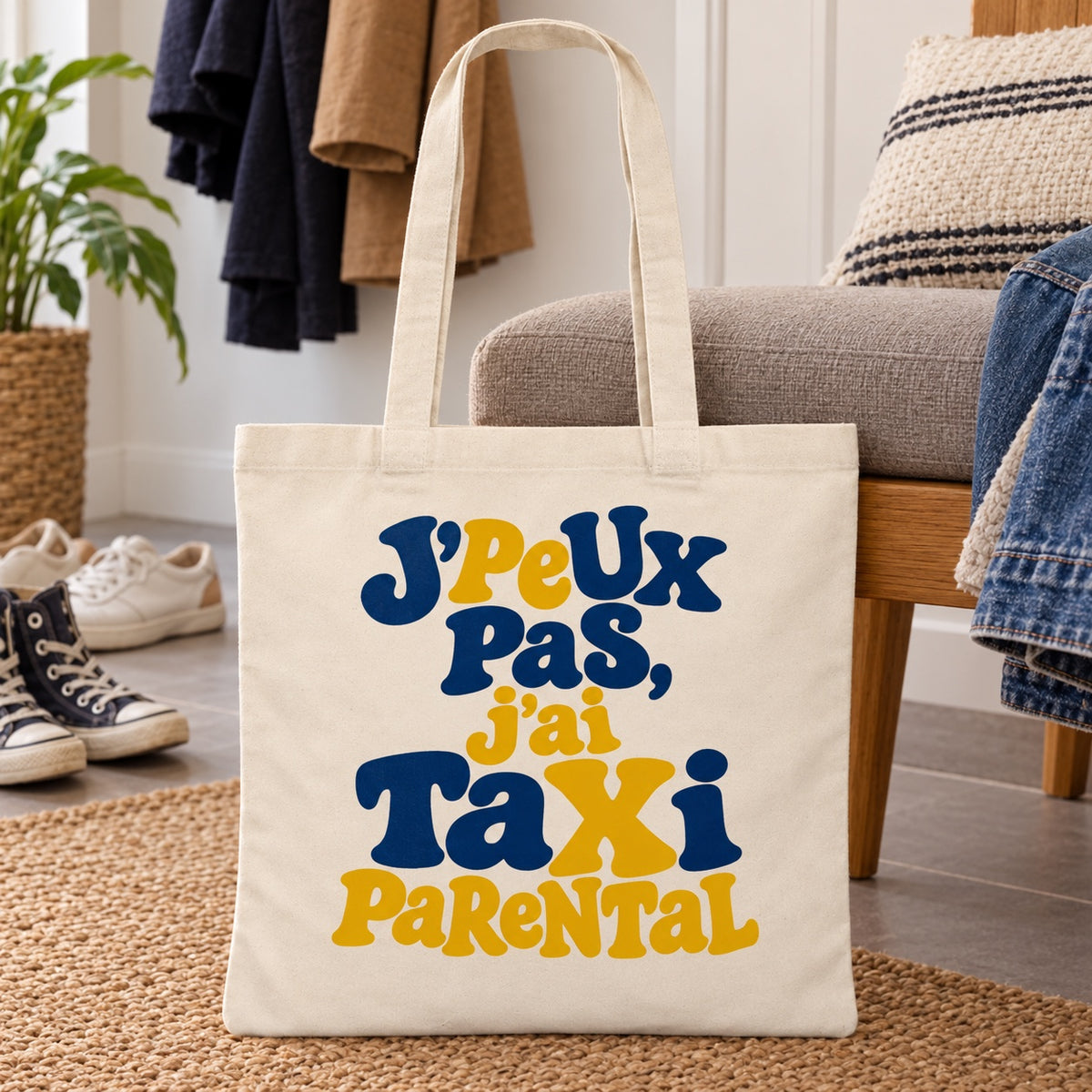 Tote bag « J'peux pas, j'ai taxi parental » Essentiel appuyé contre un fauteuil dans l'entrée