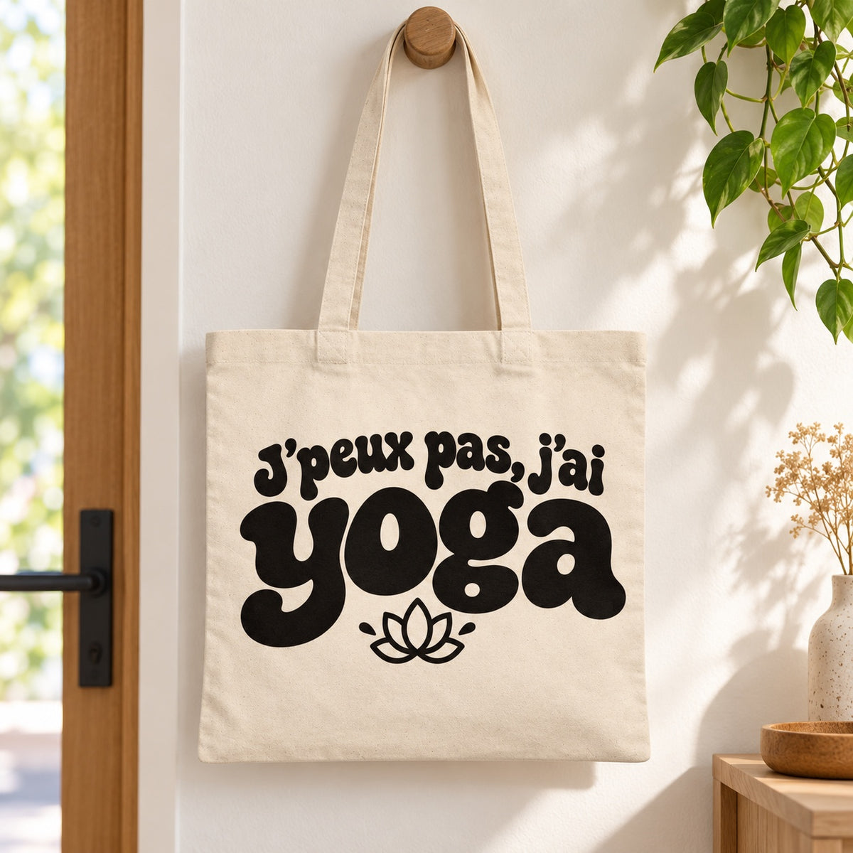 Tote bag « J'peux pas, j'ai yoga » Essentiel suspendu à une patère dans une entrée lumineuse