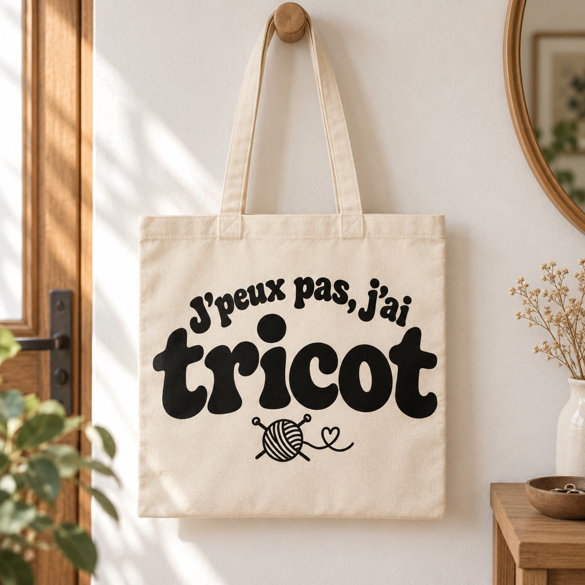 Tote bag « J'peux pas, j'ai tricot » Essentiel suspendu à une patère dans une entrée lumineuse