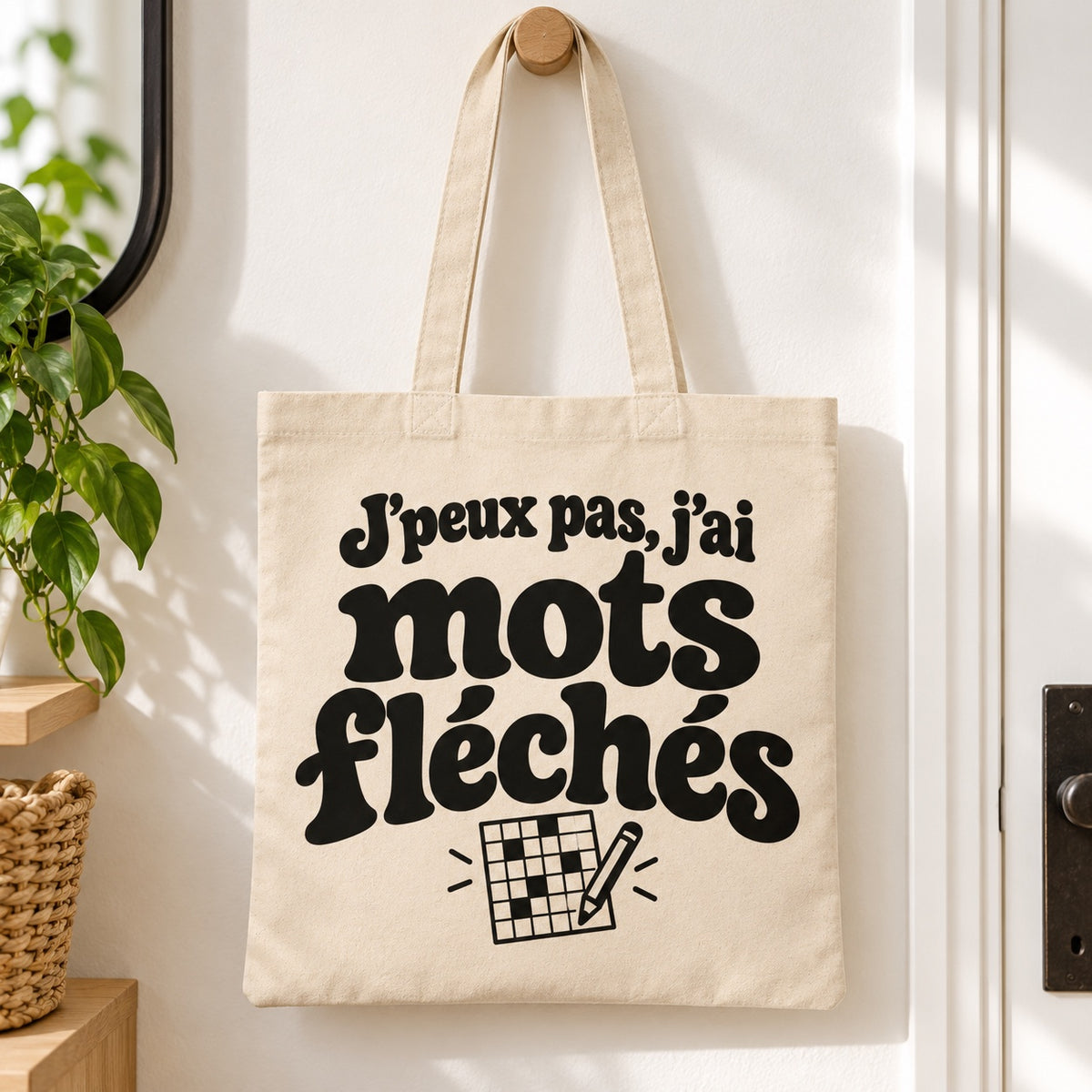 Tote bag « J'peux pas, j'ai mots fléchés » Essentiel suspendu à une patère dans une entrée lumineuse
