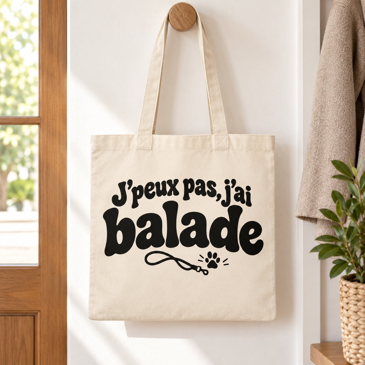 Tote bag « J'peux pas, j'ai balade » Essentiel suspendu à une patère dans une entrée lumineuse